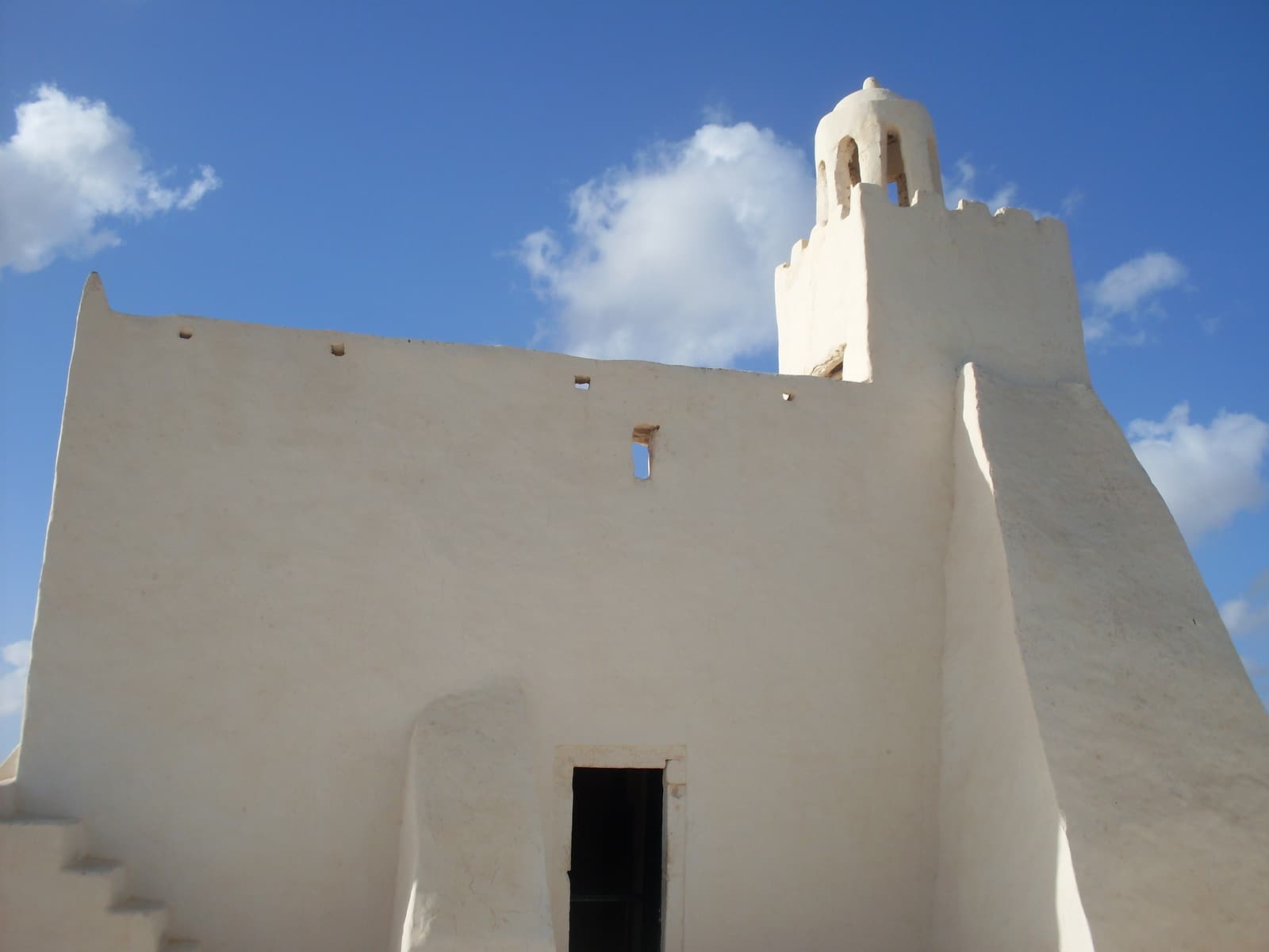 The whitewashed walls and small minaret of Fadhloun mosque against a blue sky