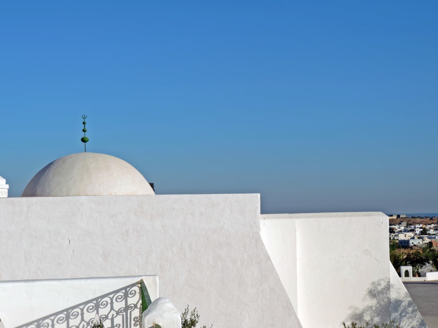 A white dome and walls above the rooftops of Guellala with the sea beyond