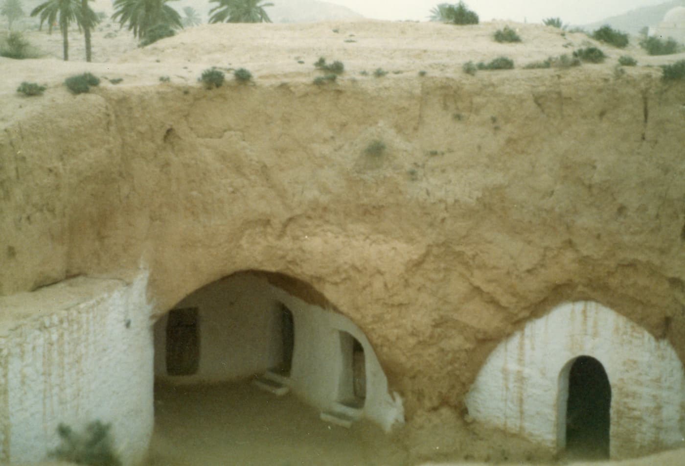Arched doorways of troglodyte rooms dug into the side of a pit in Matmata